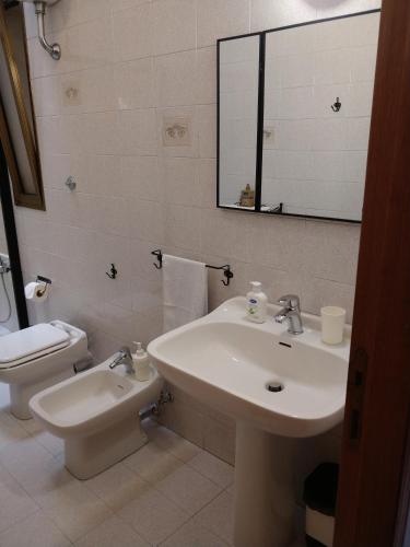 a bathroom with a sink and a toilet and a mirror at Isi GuestHouse in Iesi