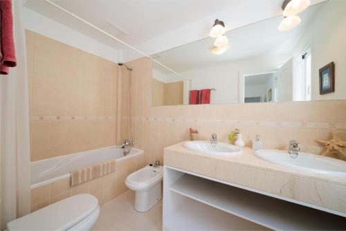 a bathroom with two sinks and a toilet and a tub at Living El Charco, piso individual in Arrecife