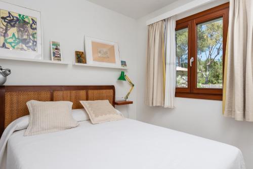 a white bedroom with a bed and a window at Amedart in Alcudia