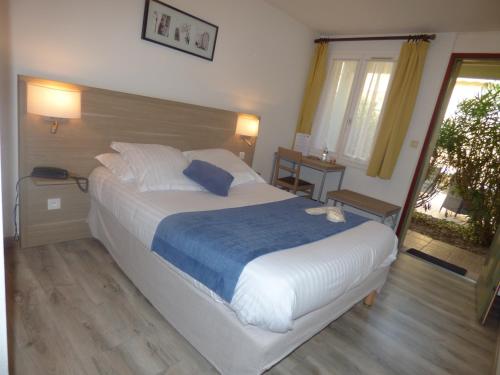 a bedroom with a large bed with a blue blanket at Hôtel Les Comtes de Pardiac in Marciac