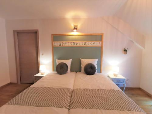 a bedroom with a large bed with two pillows at Le pavillon de l'herboriste 14p jacuzzi jardin in Tintigny
