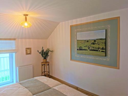 a bedroom with a picture on the wall and a bed at Le pavillon de l'herboriste 14p jacuzzi jardin in Tintigny