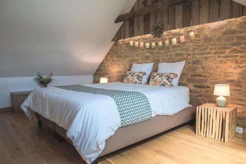 a bedroom with a large bed and a brick wall at Le pavillon de l'herboriste 14p jacuzzi jardin in Tintigny