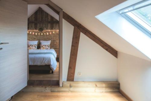 a bedroom in a loft with a bed and a window at Le pavillon de l'herboriste 14p jacuzzi jardin in Tintigny