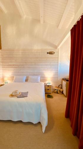 a bedroom with a large white bed with red curtains at Hôtel Île de Lumière in La Cotinière