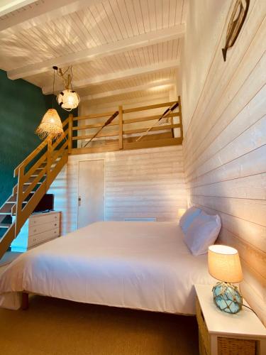 a bedroom with a white bed and a staircase at Hôtel Île de Lumière in La Cotinière