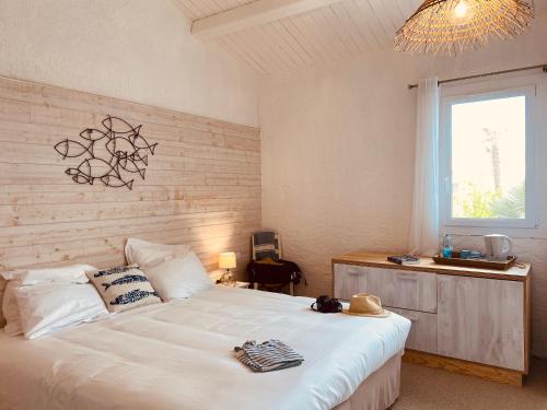 a bedroom with a large white bed and a window at Hôtel Île de Lumière in La Cotinière