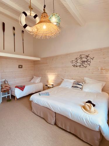 a bedroom with two beds and a chandelier at Hôtel Île de Lumière in La Cotinière