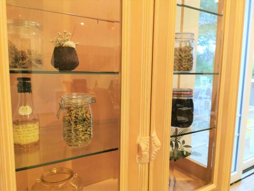 a cabinet filled with glass jars with flowers in it at Le pavillon de l'herboriste 14p jacuzzi jardin in Tintigny