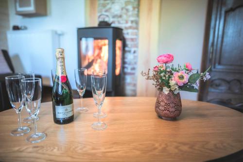 a table with glasses and a bottle of wine and flowers at Le pavillon de l'herboriste 14p jacuzzi jardin in Tintigny
