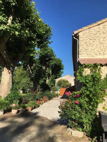 a walkway with flowers and a building and trees at Désir'ôôm in Cabannes