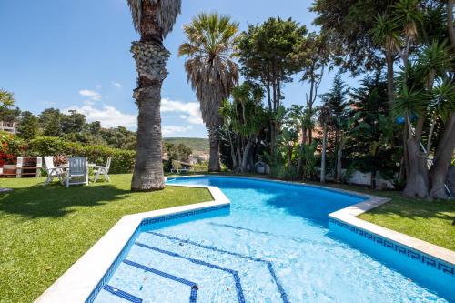a swimming pool in a yard with palm trees at Rent4rest Sesimbra 4Bdr Ocean View and Private Pool Villa in Sesimbra