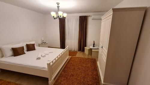 a bedroom with a white bed with a chandelier at CASA LUCA in Moldova Nouă