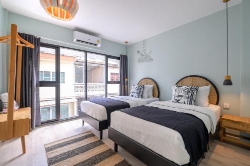 a bedroom with two beds and a large window at The Mellow at Thong Lo in Bangkok