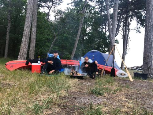 two men sitting next to a tent and a fire at Villa Wiegand - a room with a view in Holbæk