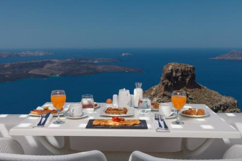 un tavolo con cibo e bevande e una vista sull'oceano di Tholos Resort a Imerovigli