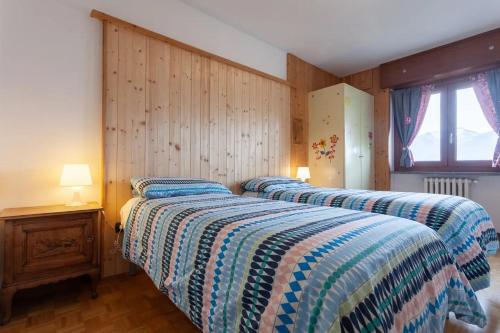 CharvensodにあるBondine Apartments in Valle d'Aostaのウッドパネルのベッドルーム1室(ベッド2台付)