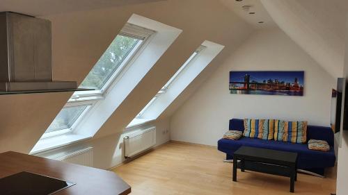 a living room with a blue couch and two windows at Ferienwohnung mit See- und Waldblick in Möhnesee