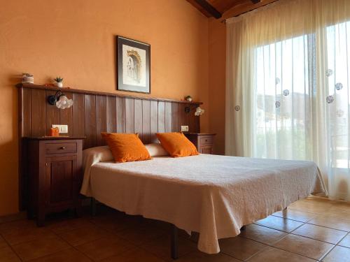 1 dormitorio con 1 cama con almohadas de color naranja y ventana en Turisme rural Can Genis, en Peralada