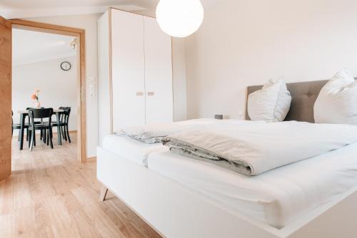 a white bedroom with a white bed and a dining room at Wallochny-Hof in Marktbreit