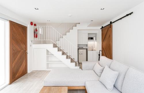 a living room with a white couch and a staircase at Any Day House Chiang mai in Chiang Mai