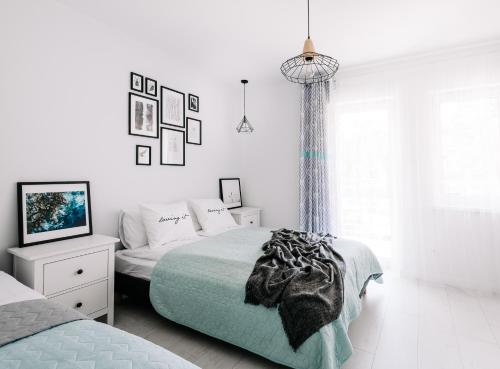 a white bedroom with a bed and a tv at SeaSide Apartment in Rowy