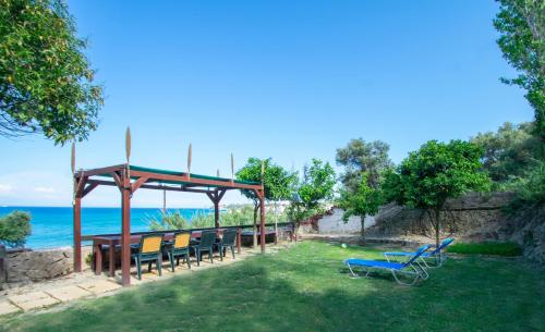 a group of chairs sitting on the grass near the ocean at Paradiso Del Mare On the Beach in Zakynthos Town