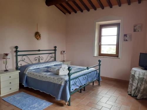 a bedroom with a bed and a window and a television at Podere Cacchini in Pienza