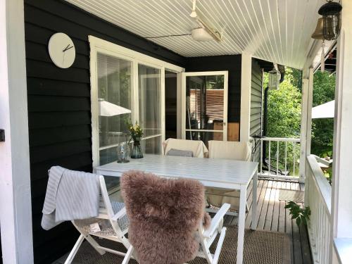 um alpendre com uma mesa branca e cadeiras em Cozy cottage near the sea em Tjustvik