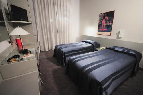 a hotel room with two beds and a television at Hotel Milano in Pistoia