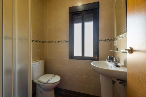 a bathroom with a toilet and a sink and a window at APARTAMENTO BOLONIA SUR A in Bolonia