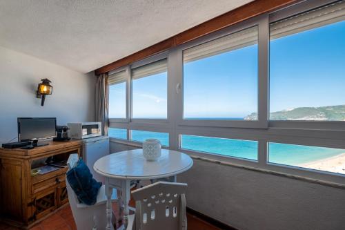 セジンブラにあるRent4rest - Sesimbra Ocean View Studioのテーブル、海の景色を望むデスクが備わる客室です。