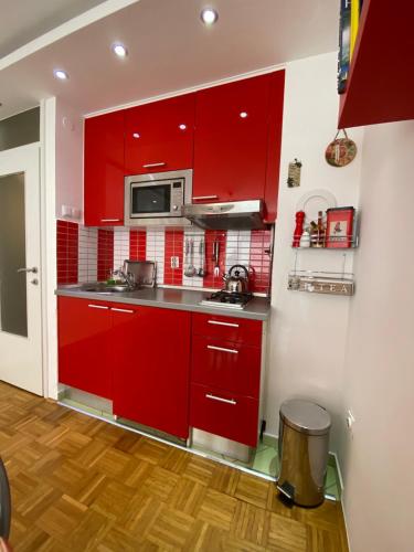a kitchen with red cabinets and a microwave at SASE Apartment in Sarajevo