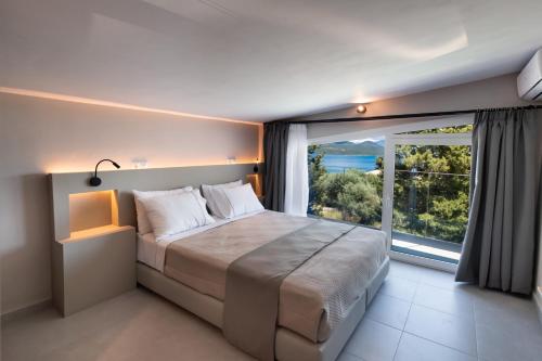 a bedroom with a large bed with a large window at ANATOLI VILLAS in Nikiana