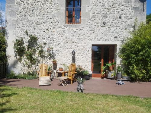 a patio in front of a stone building with two chairs at En pleine nature in Bonneuil-en-Valois