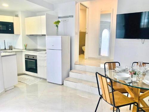 a white kitchen with a table and chairs in it at Guest House Beach & Fun in Playa de las Americas
