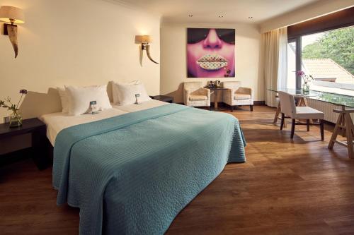 a bedroom with a bed with a blue blanket on it at Van der Valk Hotel Arnhem in Arnhem