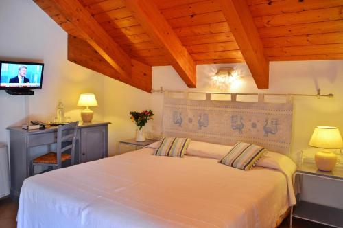 a bedroom with a white bed and a television at Pessighette Dimora Di Campagna in Bosa