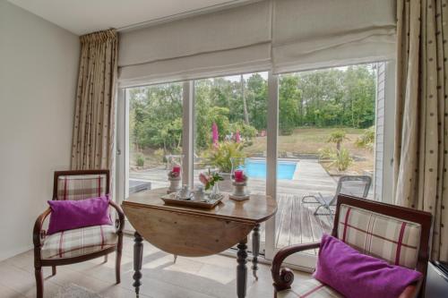 - un salon avec une table, des chaises et une grande fenêtre dans l'établissement Villa Vent-Couvert, à Le Touquet-Paris-Plage