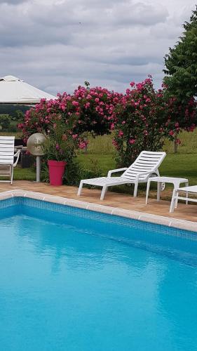 dos sillas blancas sentadas junto a una piscina en Le Gîte De L'Ouche Charlot, en Maux