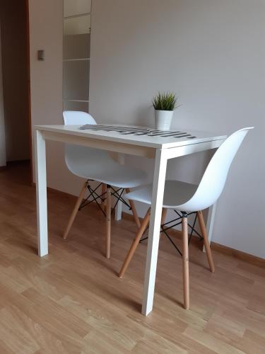 a white table with two white chairs and a potted plant at O.W. MEGA nad jeziorem in Żywiec