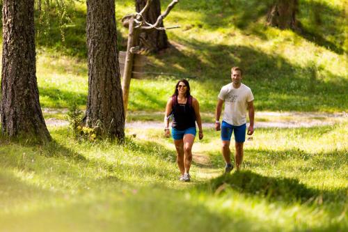 a man and woman walking down a path in a park at Brunelle Seiser Alm Lodge in Alpe di Siusi