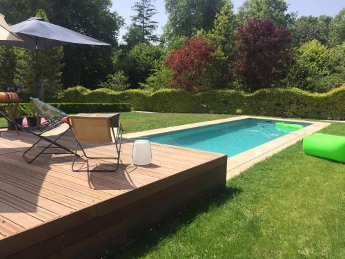 a deck with a pool and a table and an umbrella at Chambres d'Hôtes Grand Bouy in Berry-Bouy