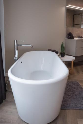 a white bath tub in a room with a table at Maison .’Eau Mer.’ in Middelkerke