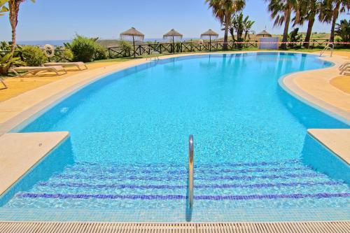 une grande piscine avec de l'eau bleue et des palmiers dans l'établissement CT 182 - Golfer's Paradise, à Mijas