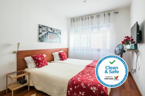 a bedroom with a bed with red pillows and a tv at Apartamento À Francos Gyn Lovers in Porto