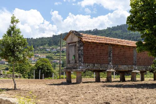 un pequeño edificio de ladrillo con una puerta de madera en troncos en Casa da Veiga, en Monção