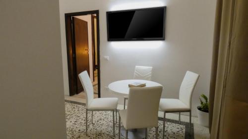 a white table and chairs with a television on a wall at Regina Margherita - Bed and Breakfast & Rooftop Lounge Bar in Siracusa