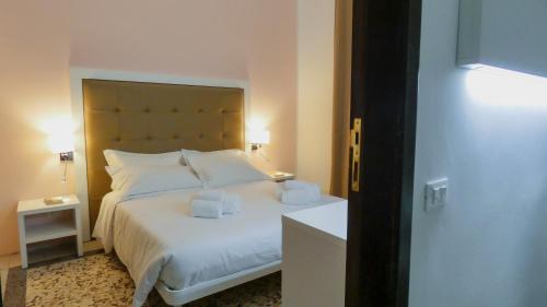 a bedroom with a large white bed with two tissues on it at Regina Margherita - Bed and Breakfast & Rooftop Lounge Bar in Siracusa