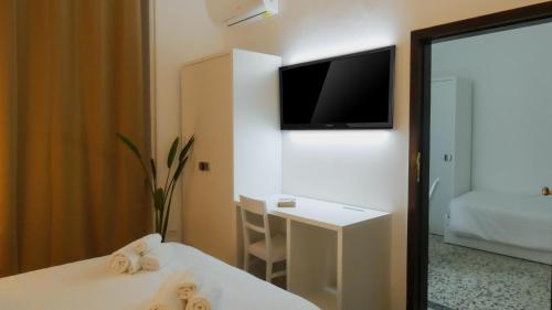 a room with a bed and a tv on a wall at Regina Margherita - Bed and Breakfast & Rooftop Lounge Bar in Siracusa